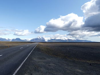 Road leading towards mountains against sky