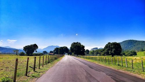 Road amidst field against sky