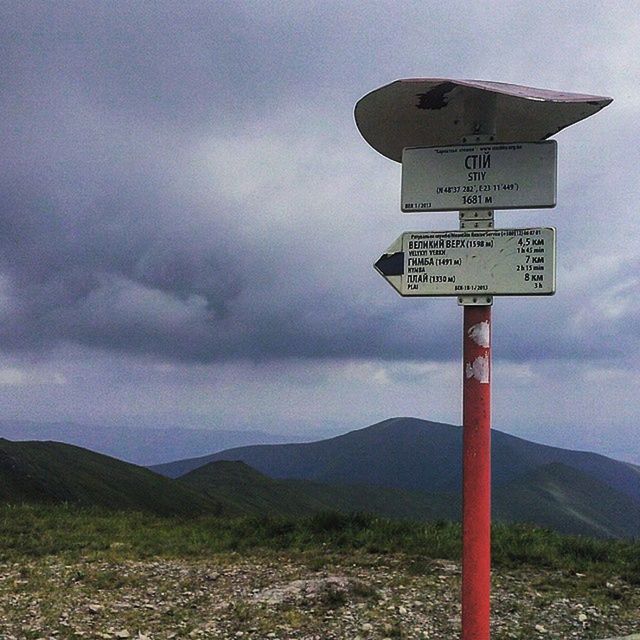 communication, text, sky, guidance, western script, mountain, road sign, landscape, cloud - sky, sign, information sign, tranquility, tranquil scene, scenics, nature, direction, beauty in nature, cloud, mountain range, cloudy