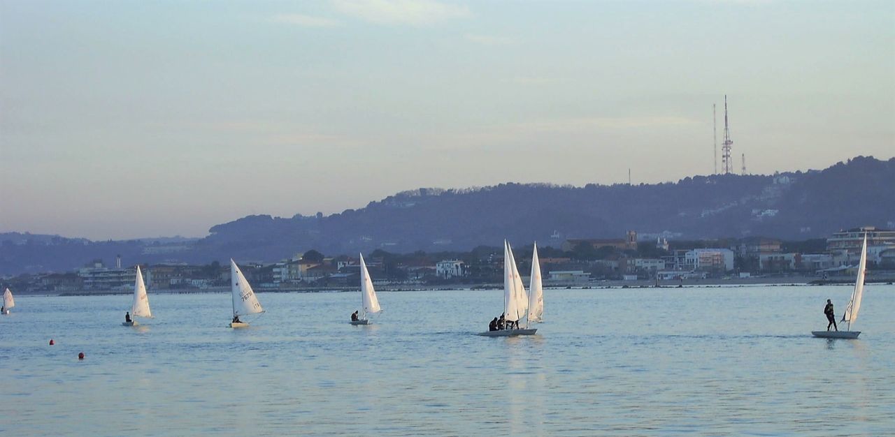 SAILBOATS SAILING ON SEA BY MOUNTAINS AGAINST SKY