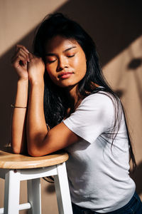 Young woman sitting on chair at home