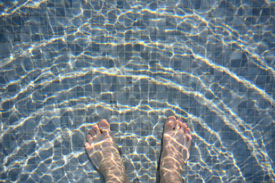 Low section of man standing in swimming pool