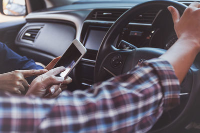 Midsection of man using mobile phone in car