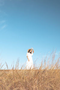 Full length of woman standing on field against clear sky