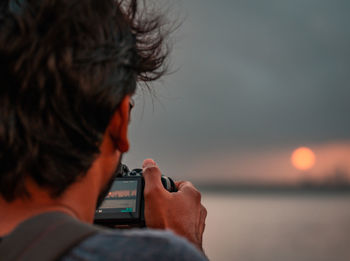 Rear view of man using mobile phone against sky