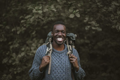 Smiling man with backpack standing in forest