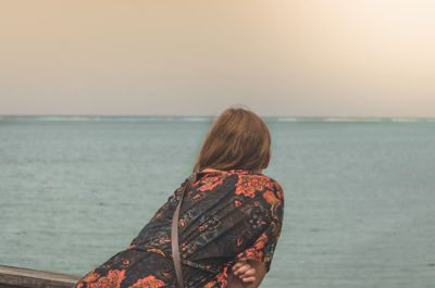Rear view of woman on beach against clear sky