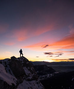 Silhouette of man on mountain peak against sky at sunset