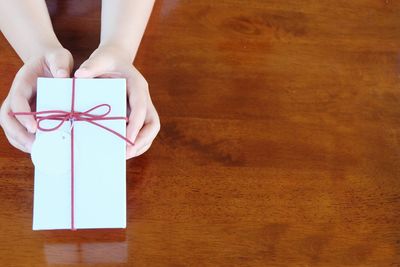 Cropped hands of woman holding gift box on table