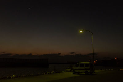 Illuminated street light against sky at night