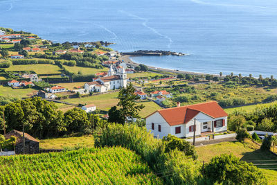 Houses and trees by sea against sky