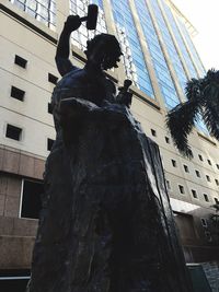 Low angle view of statue in front of building against sky