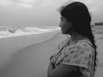 Side view of thoughtful woman standing on shore at beach