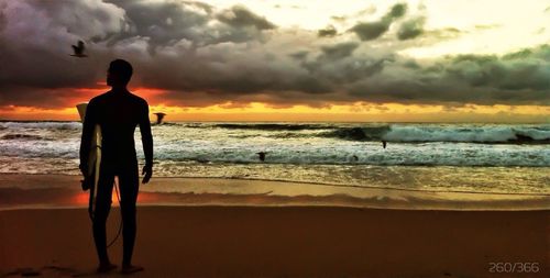 Scenic view of beach against cloudy sky at sunset