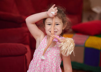 Portrait of a young girl in the livingroom at home making faces and signs of the camera