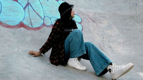 Side view of woman sitting on snow covered wall