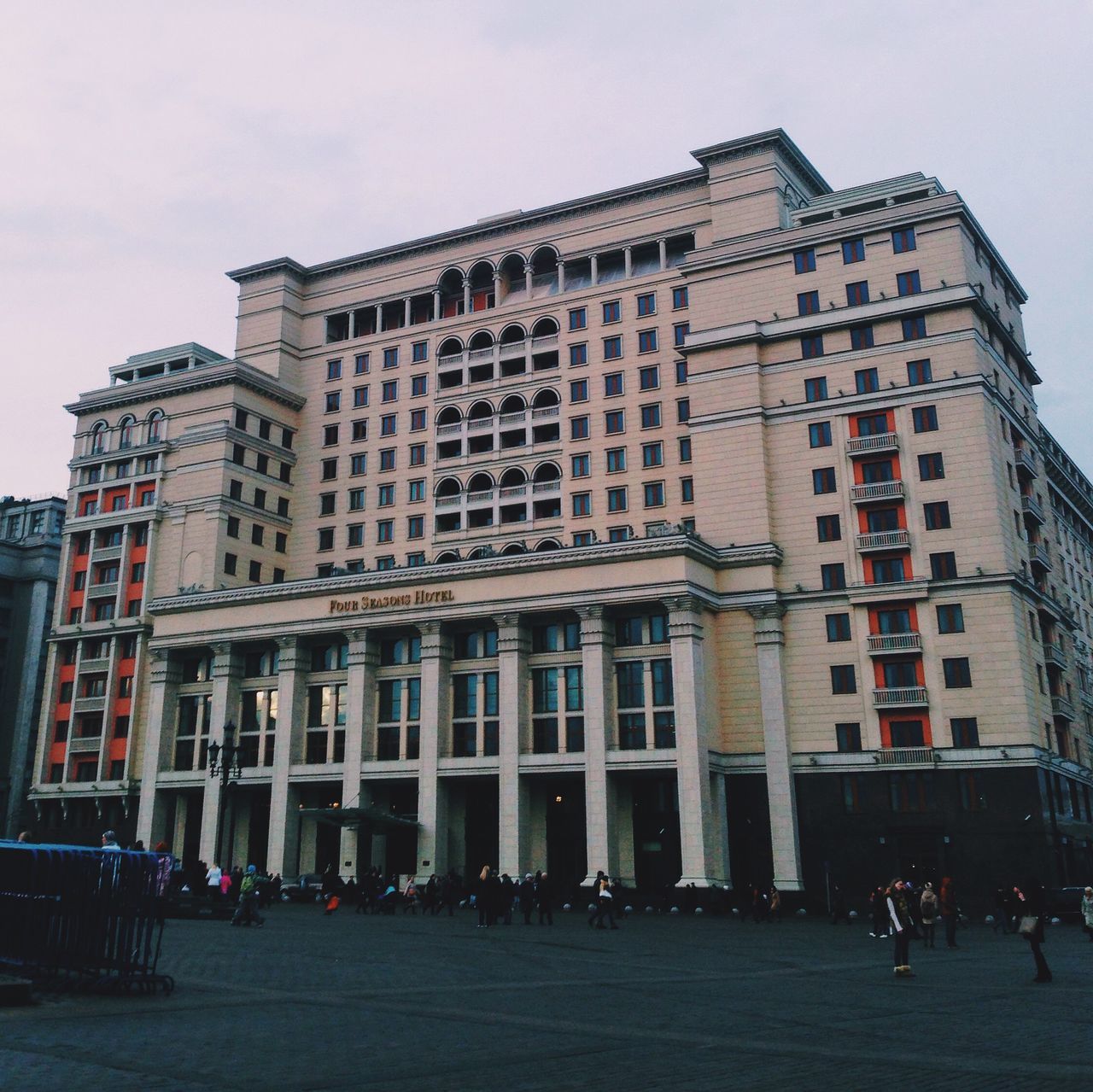 building exterior, architecture, built structure, city, sky, large group of people, street, building, city life, low angle view, window, facade, outdoors, travel destinations, day, incidental people, person, residential building, city street