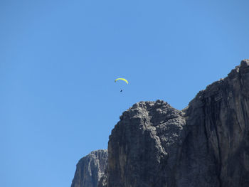 Paraglider with his yellow parachute flying near high italian mountains . dolomites, italy