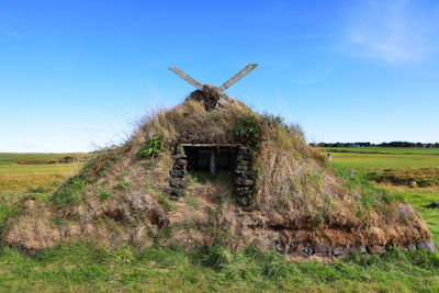 Traditional windmill on field against clear blue sky