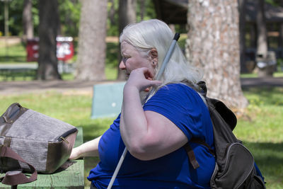 Side view of woman sitting on bench in park