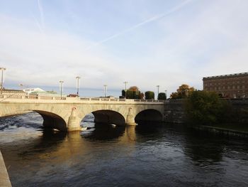 Arch bridge over river against sky in city