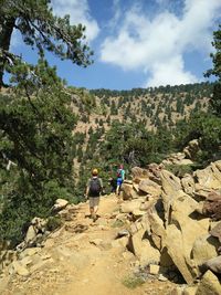 Rear view of people walking on mountain against sky