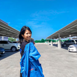 Young woman standing against blue sky