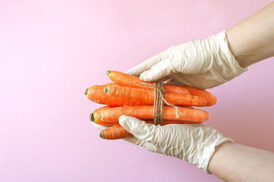 Close-up of hand holding orange against white background