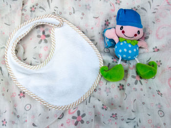 High angle view of toy with baby bib on bed at home