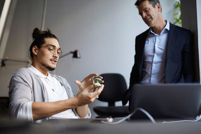 Male entrepreneur discussing with bank manager over solar toy car in creative office