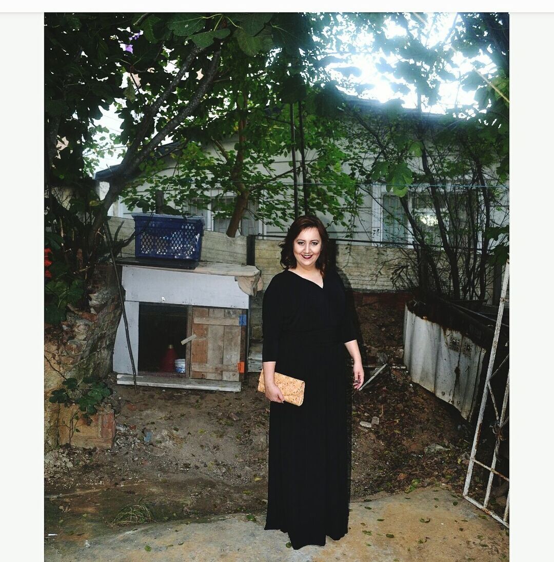 PORTRAIT OF WOMAN STANDING AGAINST TREES