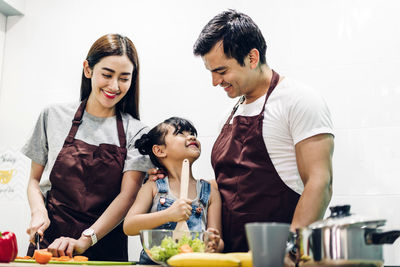 Happy friends looking away while standing in kitchen