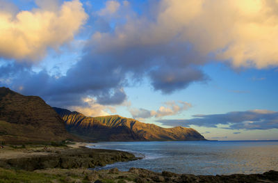 Scenic view of sea by mountains against cloudy sky at hawaii islands