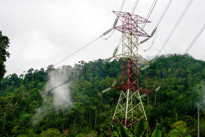 High-voltage electric towers in the fog against the background of the forest.