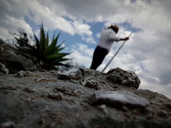 Low angle view of man standing on rock against sky