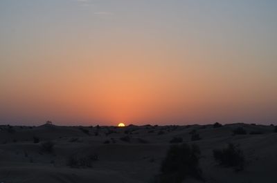 Scenic view of desert against clear sky during sunset