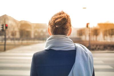 Rear view of woman standing on street against sky