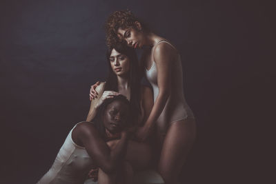 Young couple sitting against black background