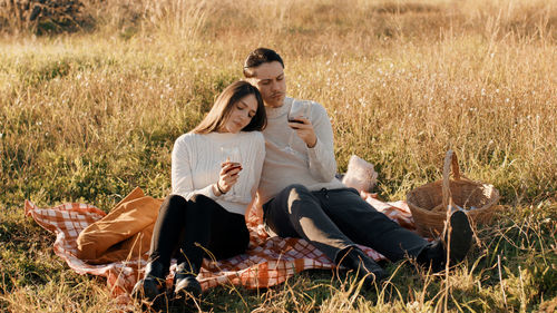 Engaged with glasses of red wine outdoor in a field