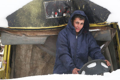 A syrian refugee child sits in an old car covered in snow. syrian refugees near the turkish border