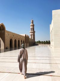 Woman walking on town square against mosque in city