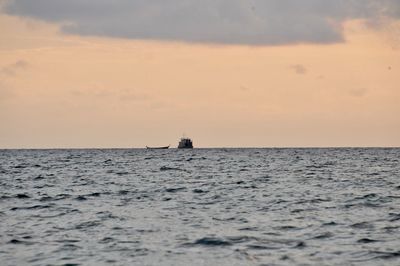 Boat sailing in sea against sky during sunset