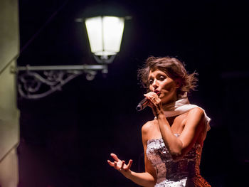Woman gesturing while singing on microphone