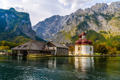 Built structure by lake and mountains against sky