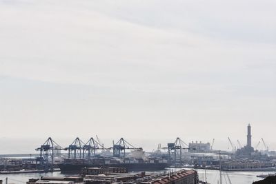 Cranes at harbor against sky