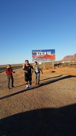 Friends standing against billboard at monument valley on sunny day