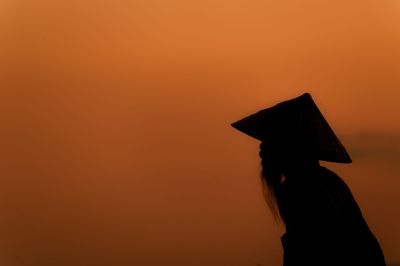 Silhouette woman standing against orange sky