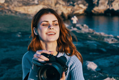 Portrait of smiling young woman holding camera