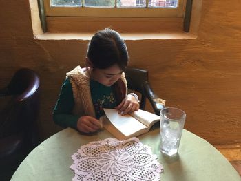 High angle view of girl reading book on table