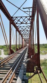 Railroad tracks by bridge against sky